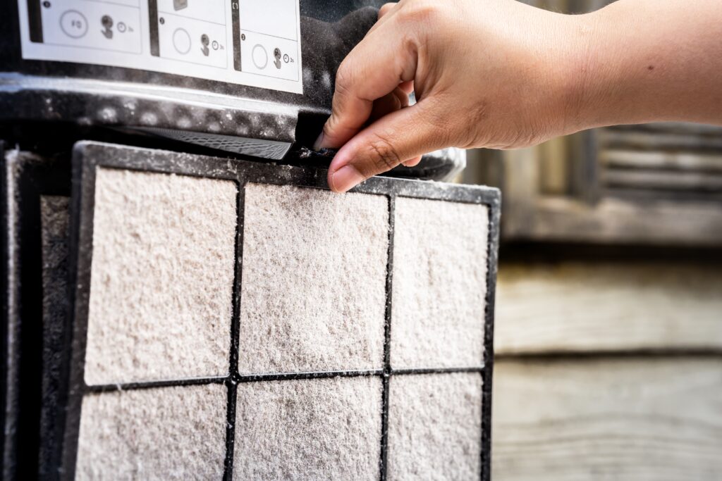 A hand is removing the filter of an air purifier, for filtering PM2.5. To bring a filter to remove dust.